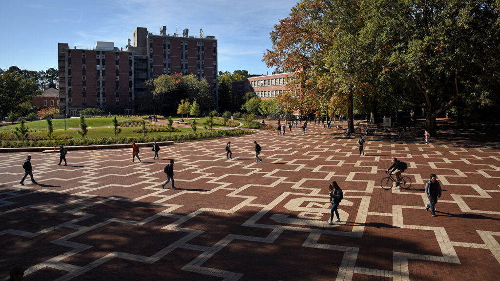 students walking across brickyard on fall day