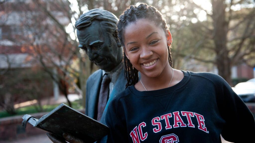 A student poses next to a statue