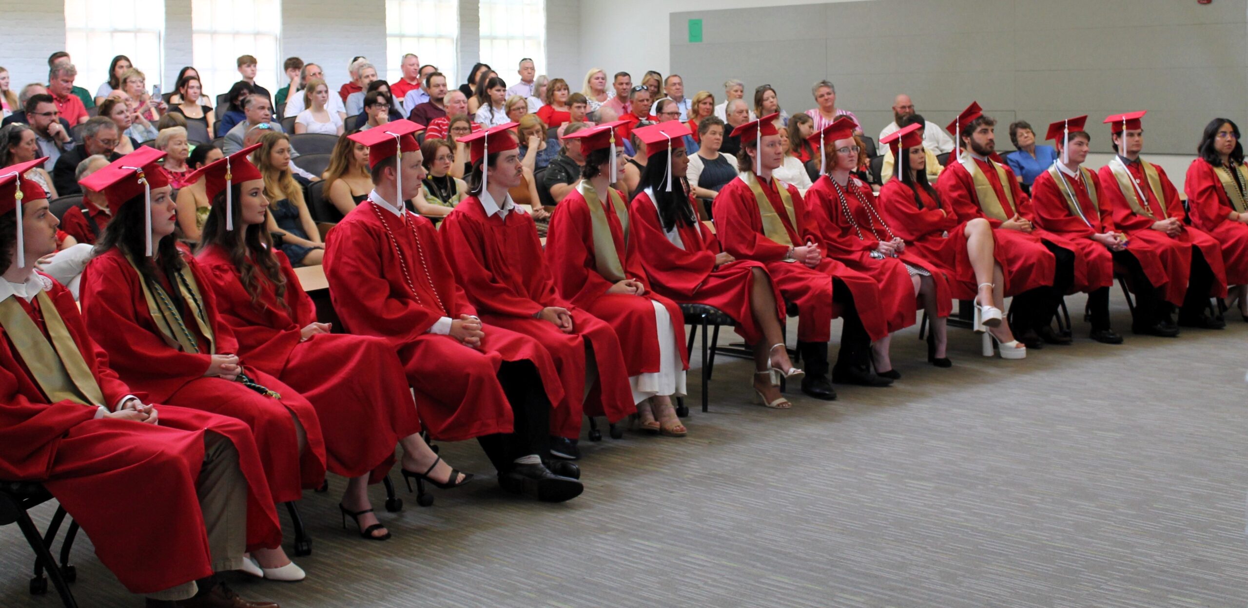 Picture of graduates sitting in front row with audience behind
